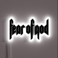 Load image into Gallery viewer, Alt text: "Neon sign displaying the phrase 'fear of god' in bold, gothic-style black lettering, outlined with a glowing white border."