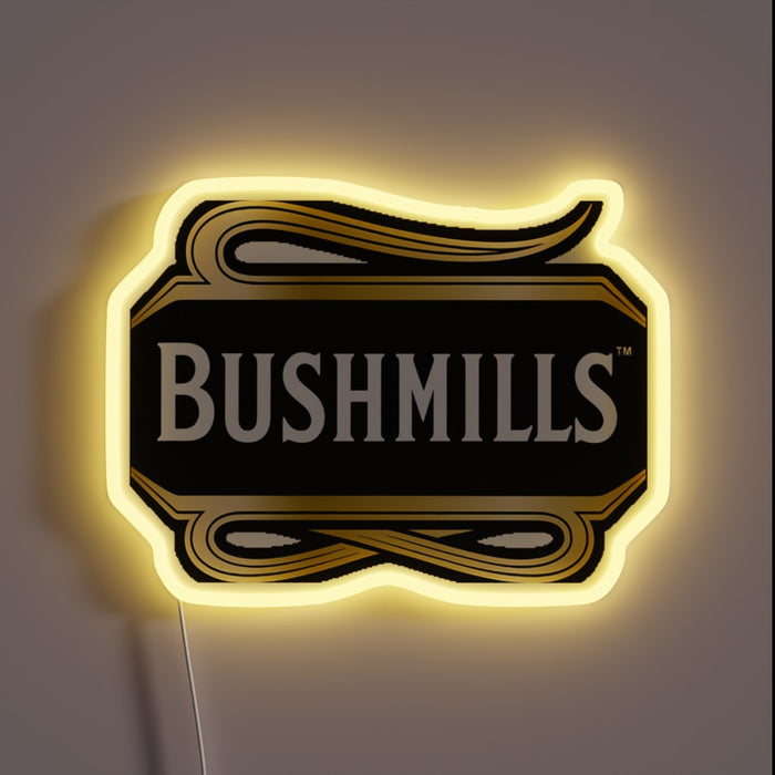 Neon sign shaped like the Bushmills whiskey logo with white text on a black and gold background, glowing with a warm yellow outline.
