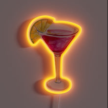 Load image into Gallery viewer, Neon sign in the shape of a red cosmopolitan cocktail glass with an orange slice garnish, glowing with a warm orange outline.
