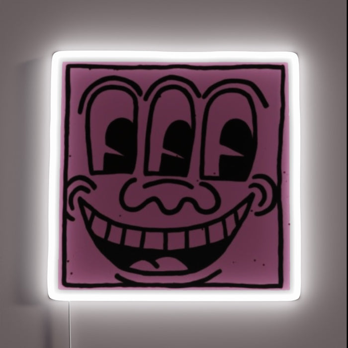 Pop art–style neon sign featuring a quirky purple face with three eyes and a wide grin, outlined by a glowing white neon frame — customneon artwork inspired by Keith Haring