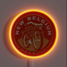 Load image into Gallery viewer, This glowing neon sign features the iconic New Belgium Brewing logo — a red cruiser bicycle set against a warm amber hue — making it a perfect tribute for craft beer lovers and brewery aficionados alike.