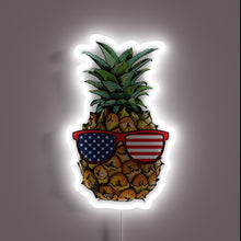 Load image into Gallery viewer, Neon sign of a pineapple wearing American flag sunglasses.
