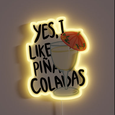 Neon sign with text “Yes, I like piña coladas” and a cocktail glass with a red umbrella.

