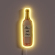 Load image into Gallery viewer, Neon sign in the shape of a rosé wine bottle with the text &quot;Rosé all day&quot; and a warm yellow glow.
