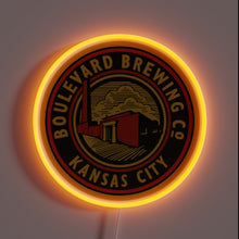 Load image into Gallery viewer, Alt text: Neon-lit round sign with &quot;Boulevard Brewing Co Kansas City&quot; logo in black, red, and gold, featuring a factory illustration.
