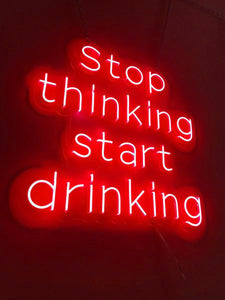 Red wall neon signs: Stop Thinking Start Drinking