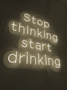 Neon that says Stop Thinking Start Drinking 